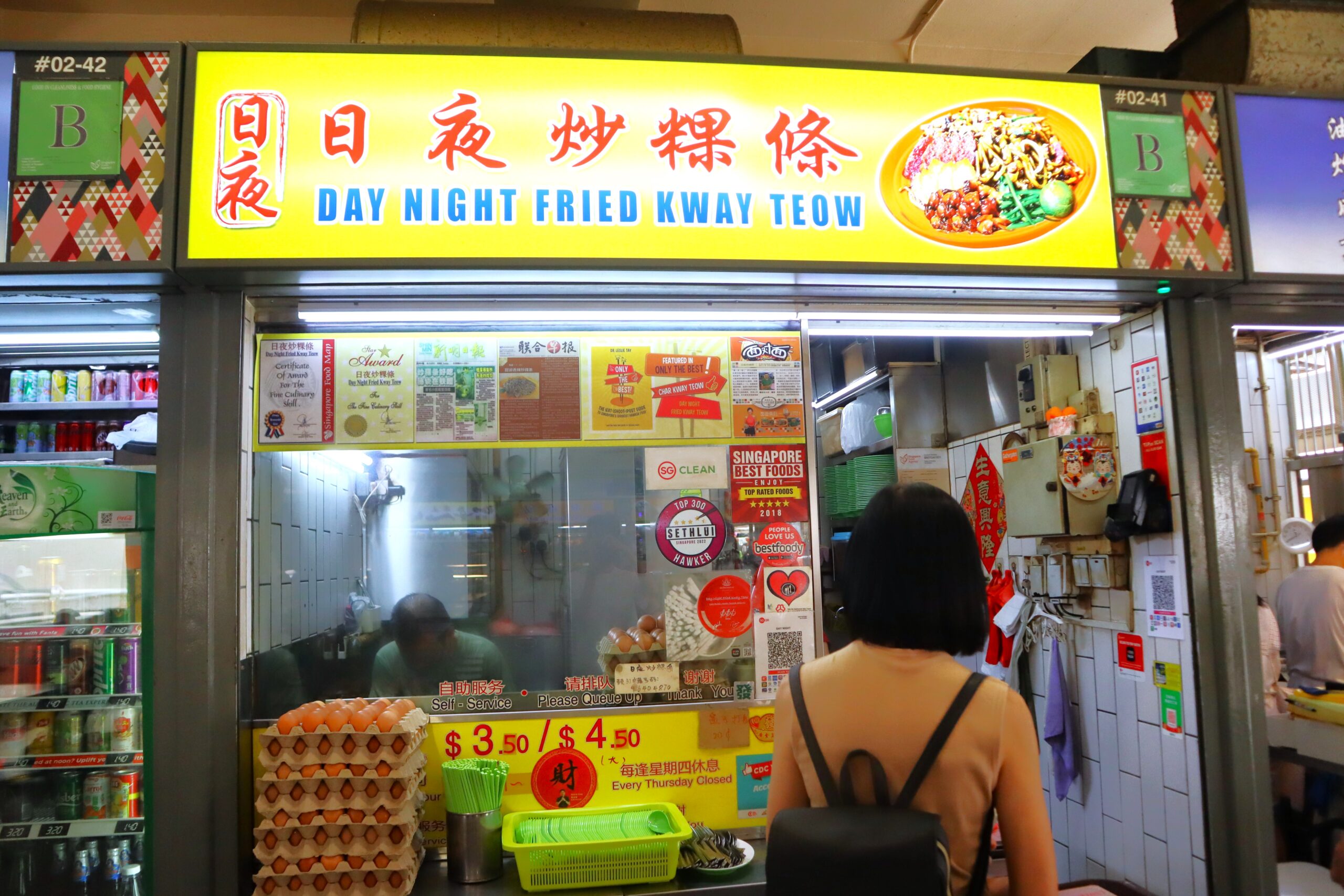 A char kway teow stall at a Singapore hawker centre, with the wok fired up and bean sprouts and noodles being stir-fried, the style of preparation at 786 Char Kway Teow