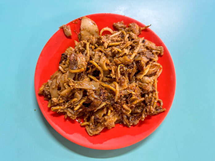 Close-up of a wok-fried char kway teow plate with charred edges, cockles and bean sprouts, the style served at 786 Char Kway Teow in Bukit Merah View Market
